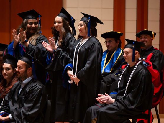 Students in graduate robes applaud at their MBA Commencement ceremony at Willamette's Atkinson Graduate School of Management