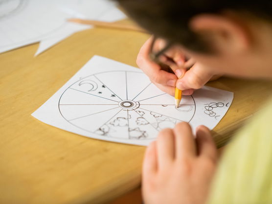 A PNCA student draws patterns on a piece of paper, filling in a disk-shaped grid