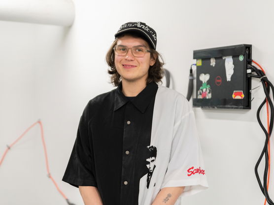 A PNCA student wearing a black and white shirt and hat in a white room