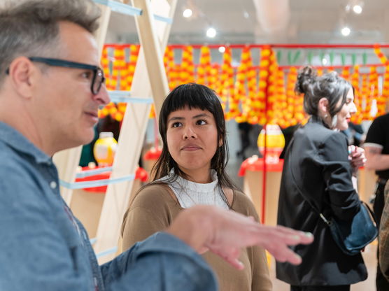 People stand around chatting in a colorful art gallery as part of a PNCA First Thursday event