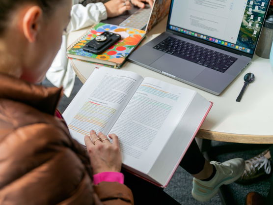 A Willamette law school student reads from a textbook in her lap with her laptop in front of her