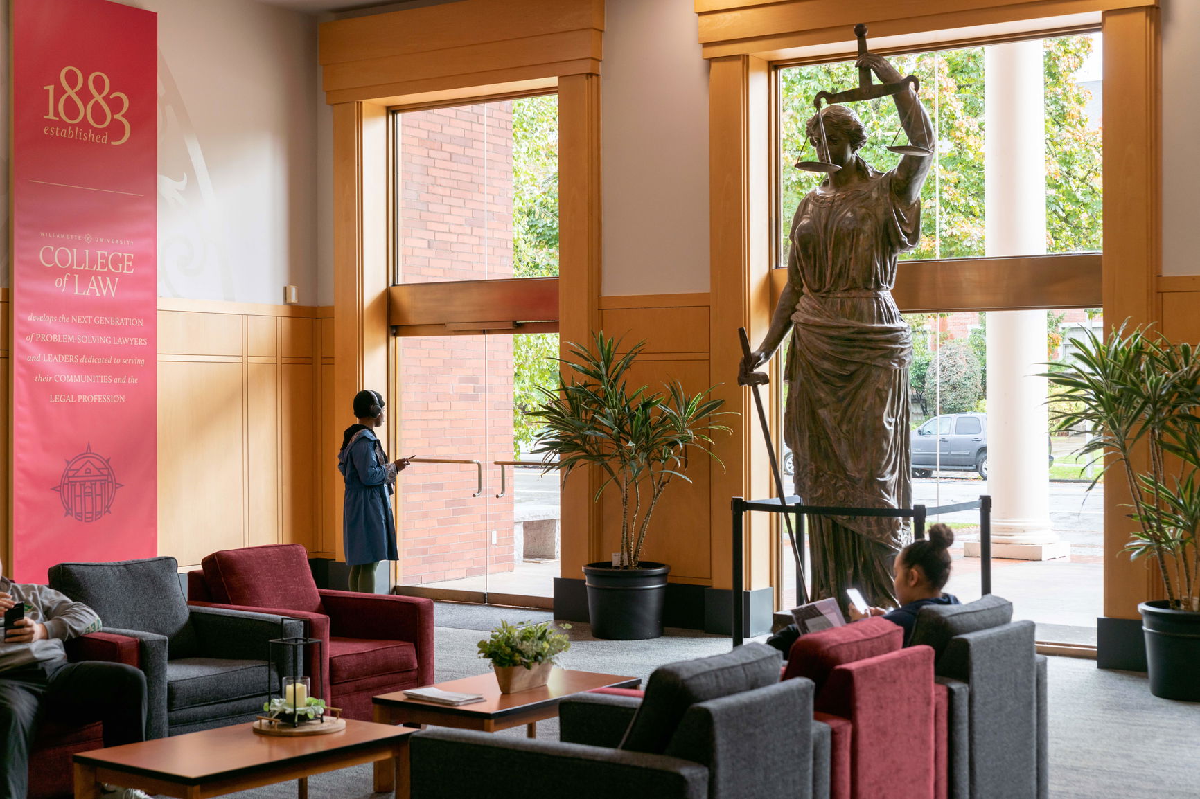 The lobby of the Willamette College of Law, including a statue of Lady Justice holding a scale on sword and two students