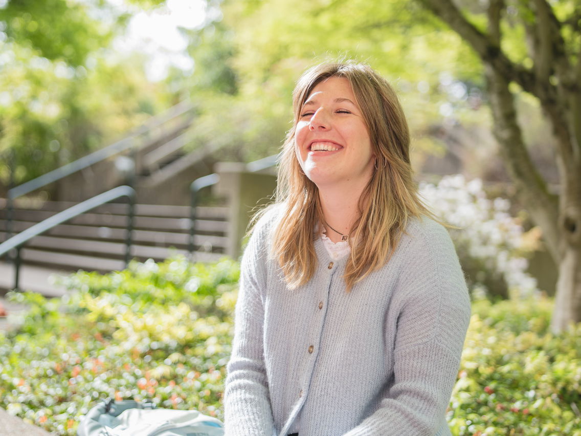 Candid shot of Madeline Hueske laughing under a tree on Willamette's Salem campus