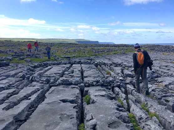 A student studying abroad and walking on a rock formation.