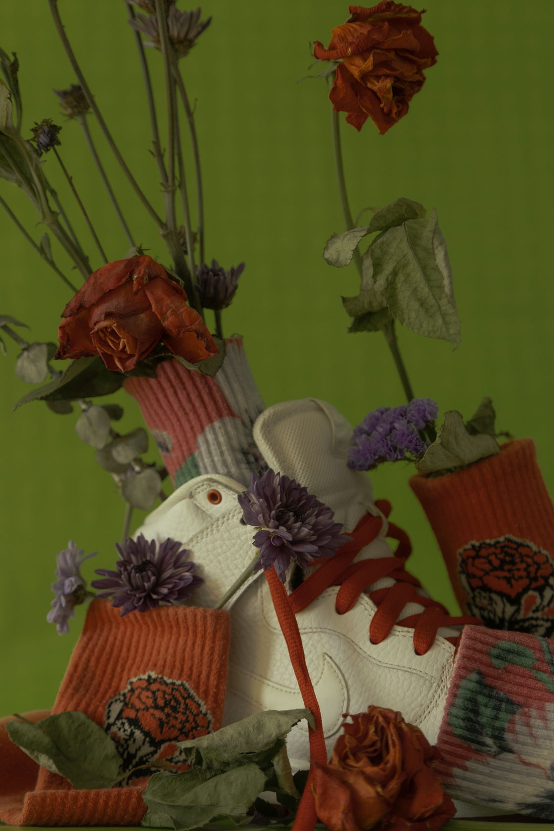 Photograph of a white shoe on a green background with red flowers