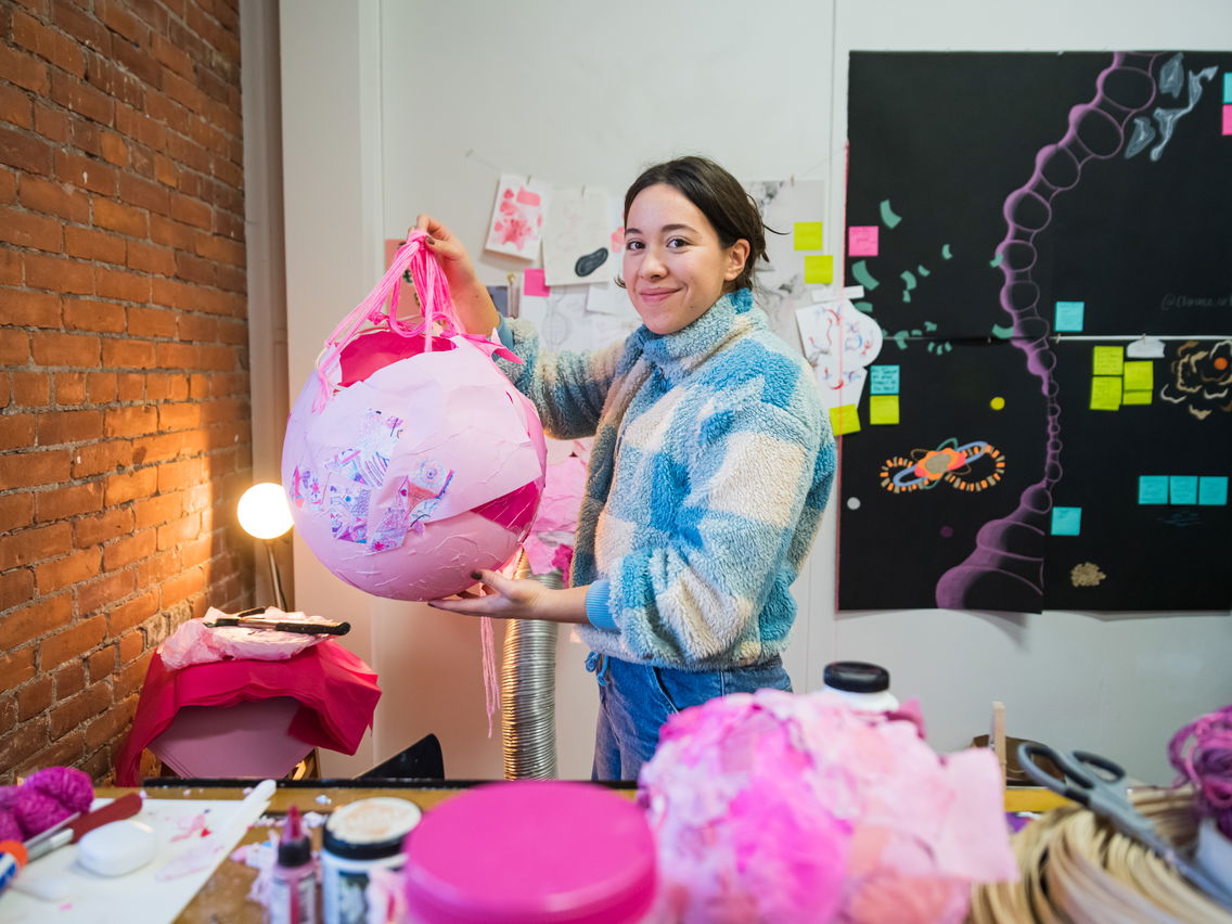 A woman holding up artwork in progress