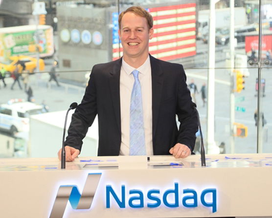 Image of alum Nathan Love sitting at the NASDAQ desk. 