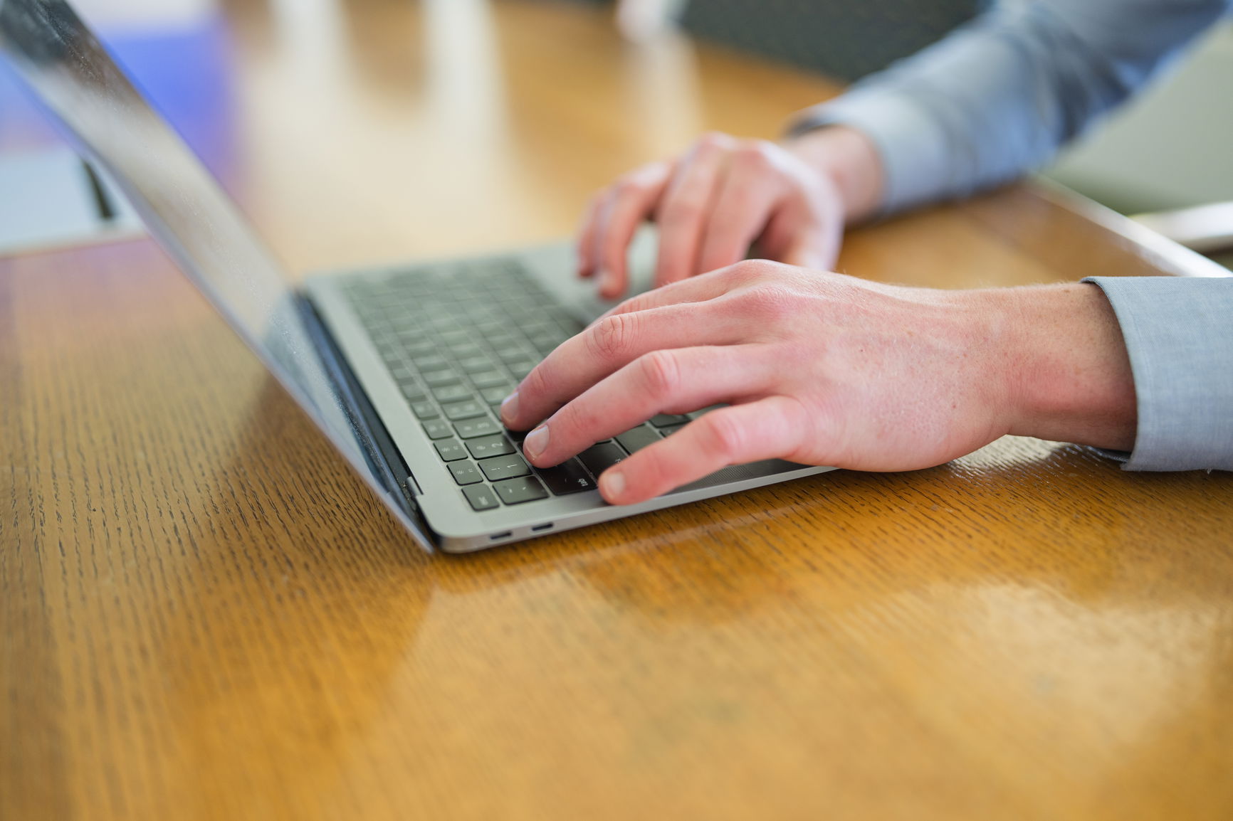 A close up image of hands and fingers typing on a Mac computer