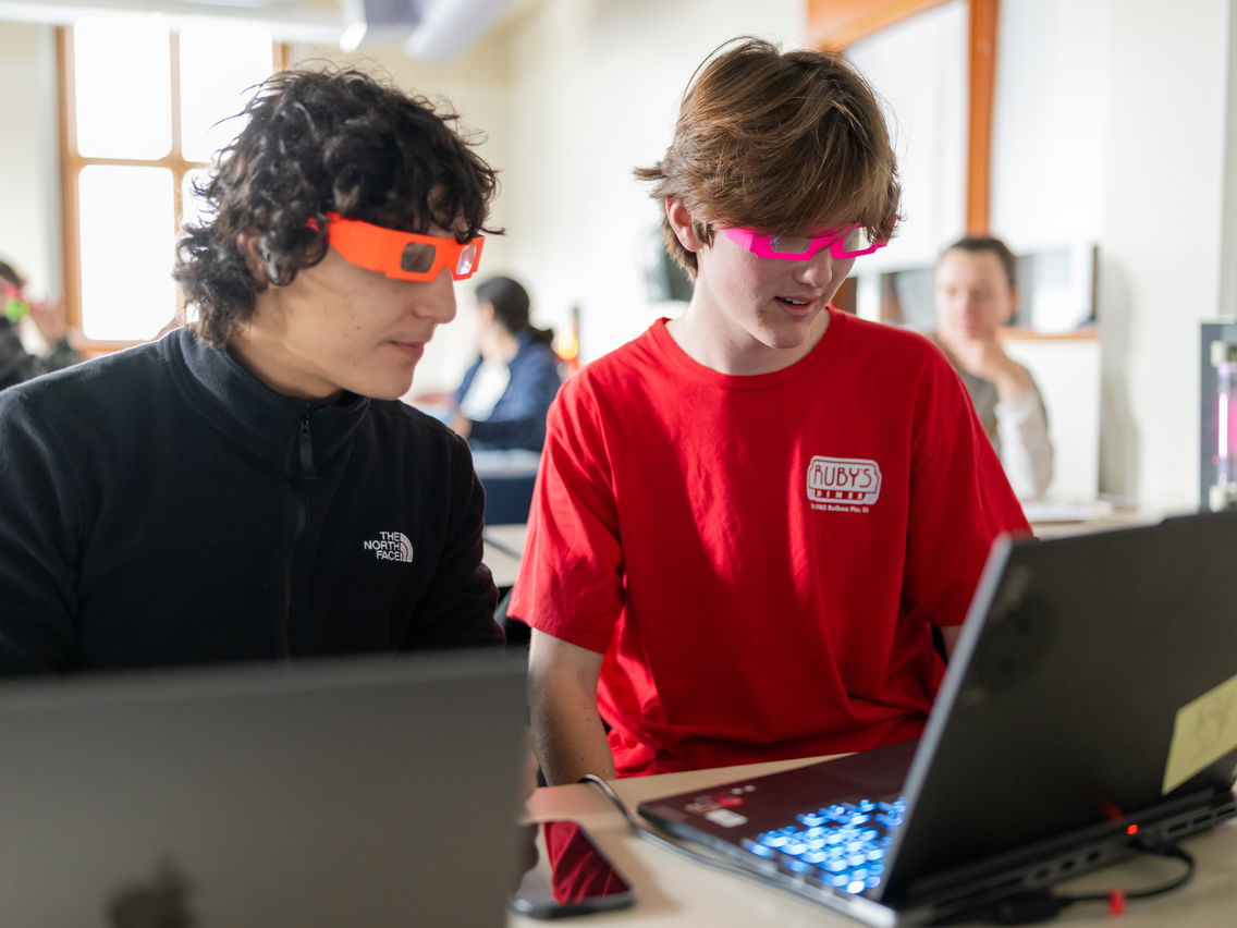 Two men with 3-D glasses looking at a laptop