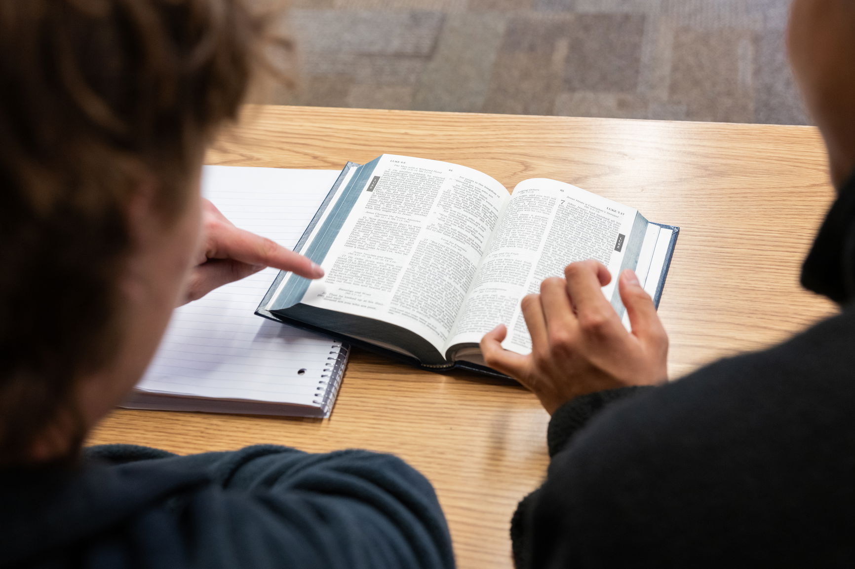 Two students reviewing text in a book