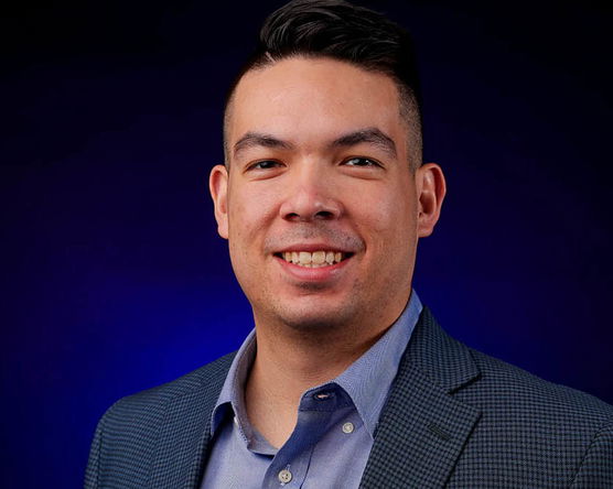 Tommy Kawamura's headshot on a dark blue background. 