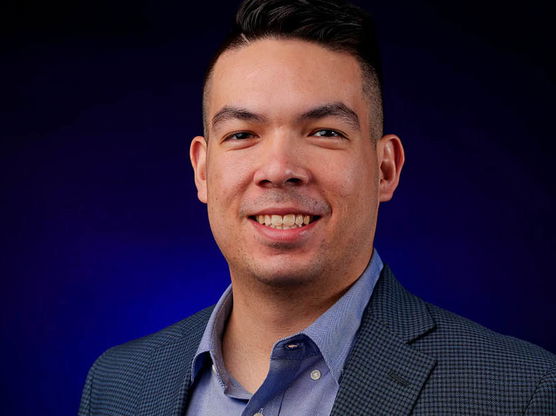 Tommy Kawamura's headshot on a dark blue background. 