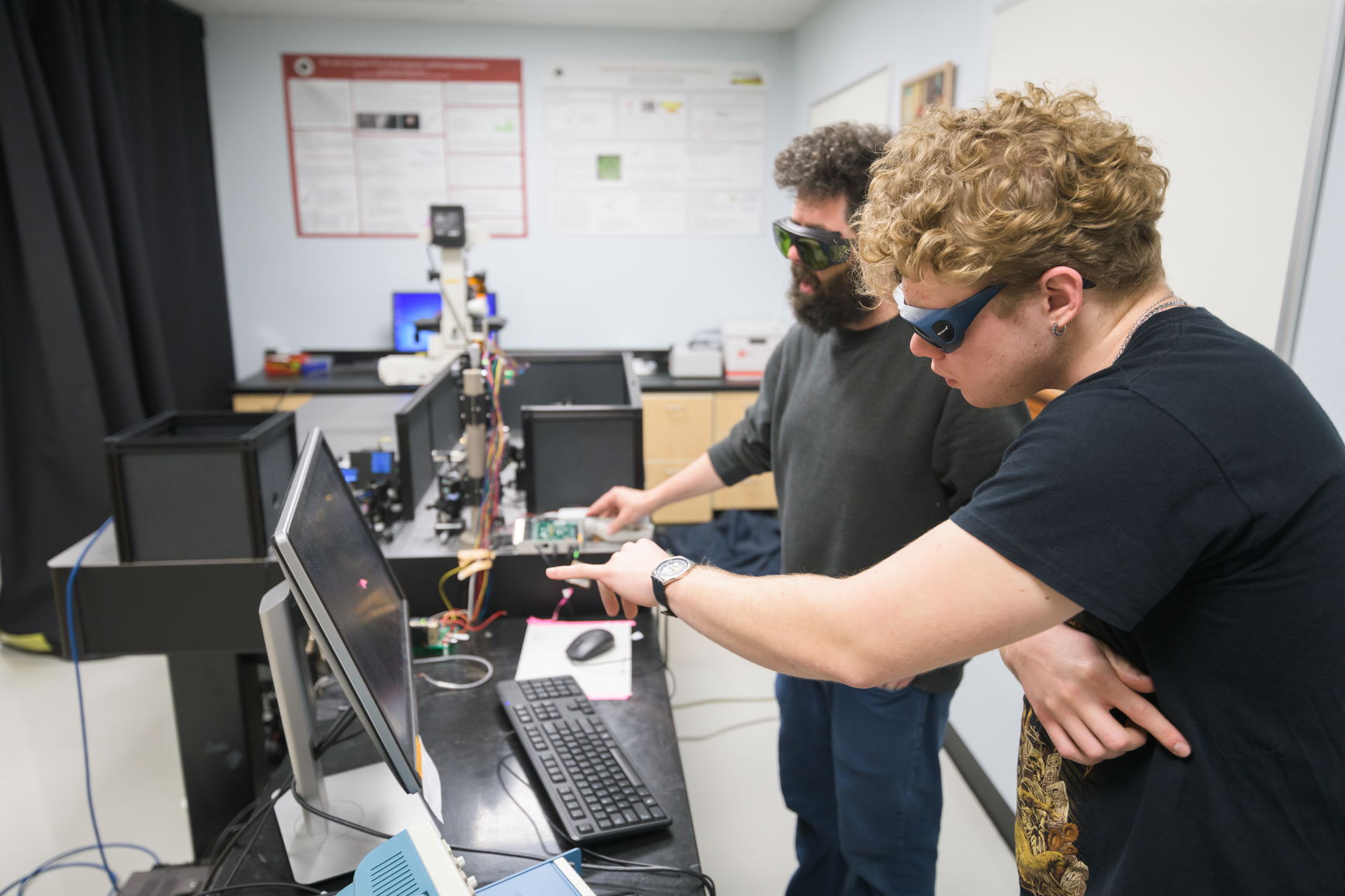 A student looking at results with a professor on a computer from a microscope