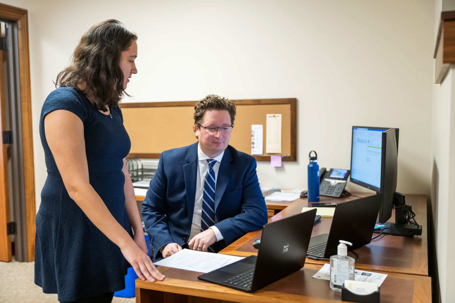 A student working with a man with a tie in a government building