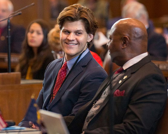 Adrian Uphoff smiling and sitting on the floor of the Oregon State Capitol