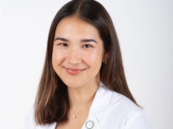 Portrait of Montana in a white lab coat against a white background. 