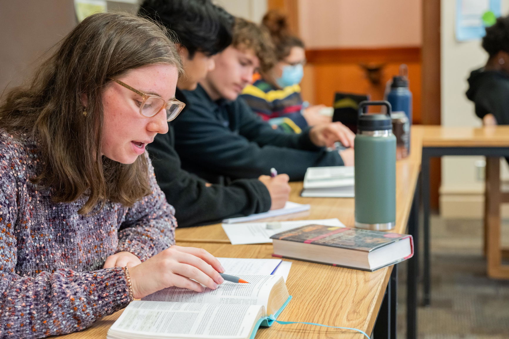 Students studying at a table in a classroom. 