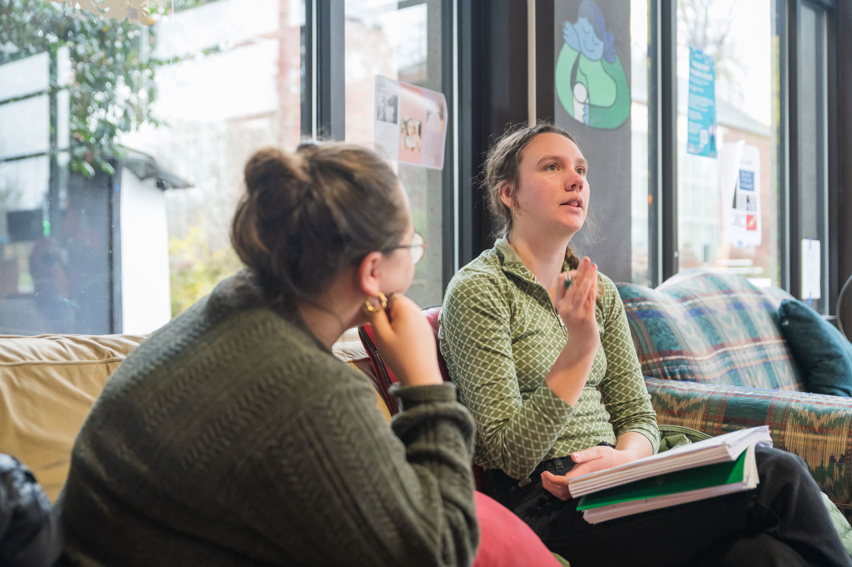 Two students sitting on a couch having a conversation.